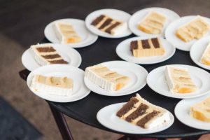 A group of white plates with slices of cake on them for a wedding celebration.