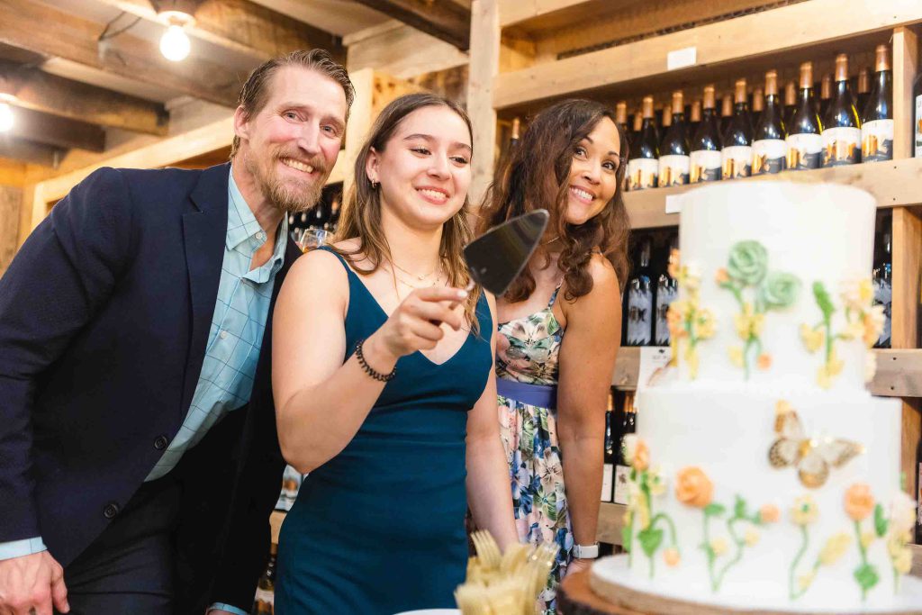A group of people cutting a birthday cake in a winery.
