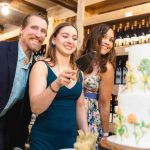 A group of people cutting a birthday cake in a winery.