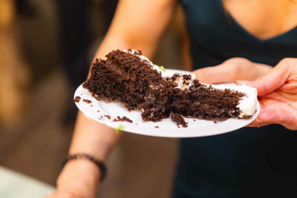 A person holding a piece of chocolate cake at a birthday party.