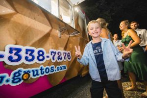 A young boy standing in front of an ice cream truck at a wedding reception.