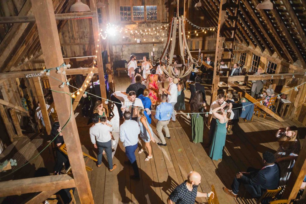A group of people dancing at a wedding reception in a barn.