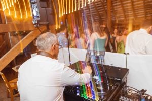 A man DJing at a wedding reception in a barn.