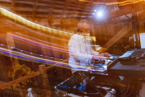 A man is playing a DJ in a wedding reception barn.