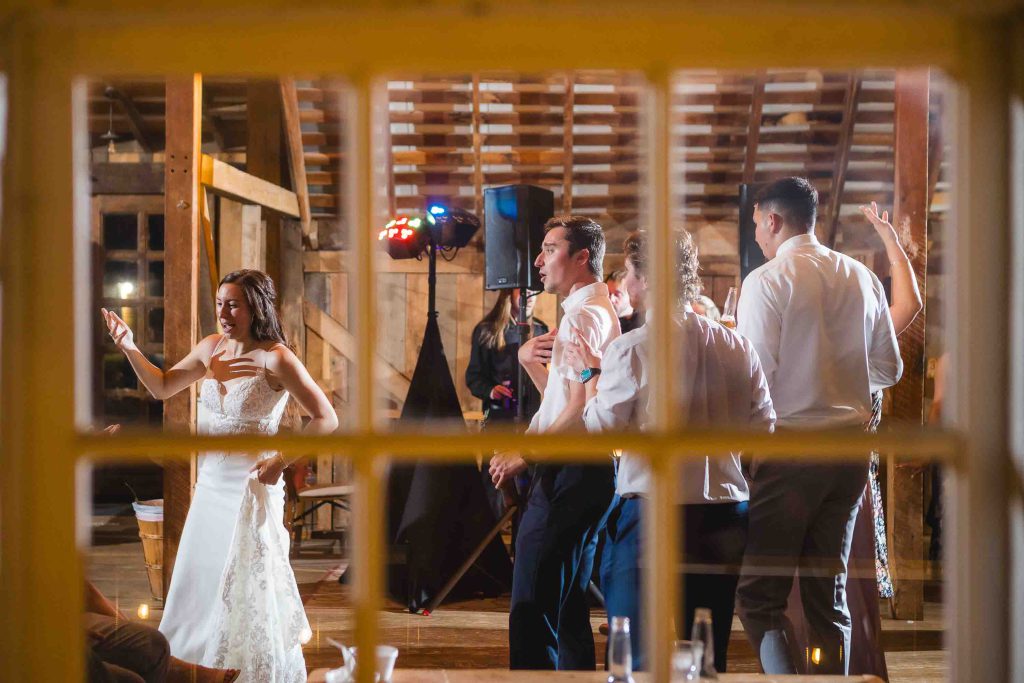 A couple at their wedding reception standing in front of a window in a barn.