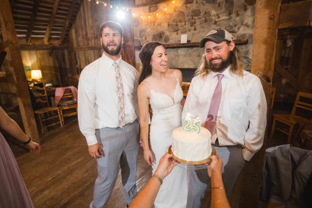 A wedding couple holding a cake during their reception in a barn.