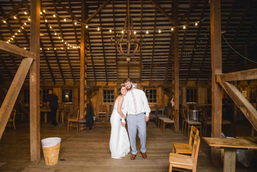 A bride and groom celebrating their wedding in a barn adorned with string lights during the reception.