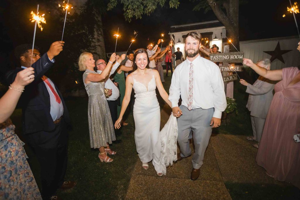 A bride and groom walk away with sparklers at their wedding reception.