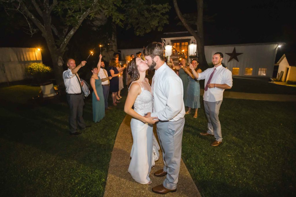 A newlywed couple sharing a kiss during their wedding reception.