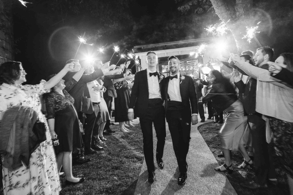 A black and white photo of a couple walking down the aisle during their wedding reception.
