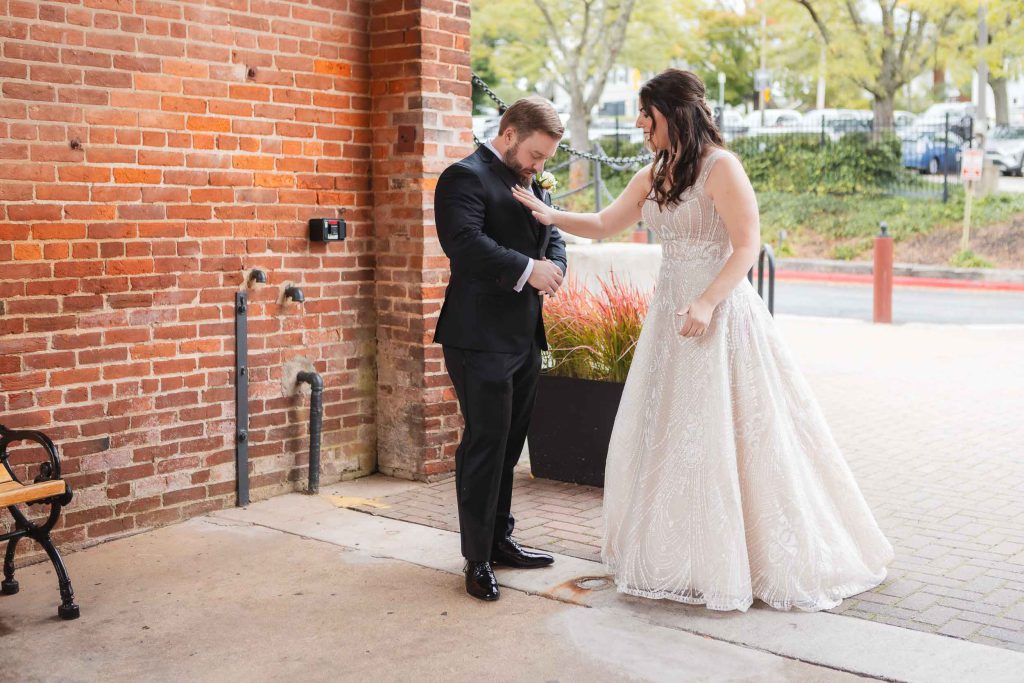 A wedding couple standing candidly in front of the historic Savage Mill building.