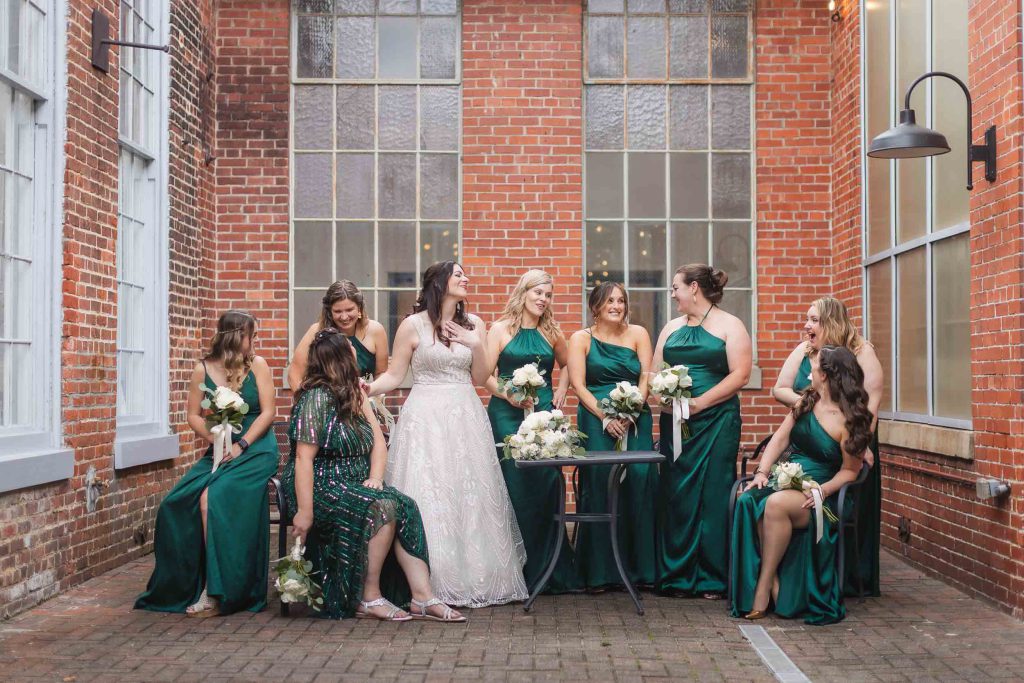 A group of bridesmaids posing for a portrait at a wedding in emerald green dresses at Savage Mill.