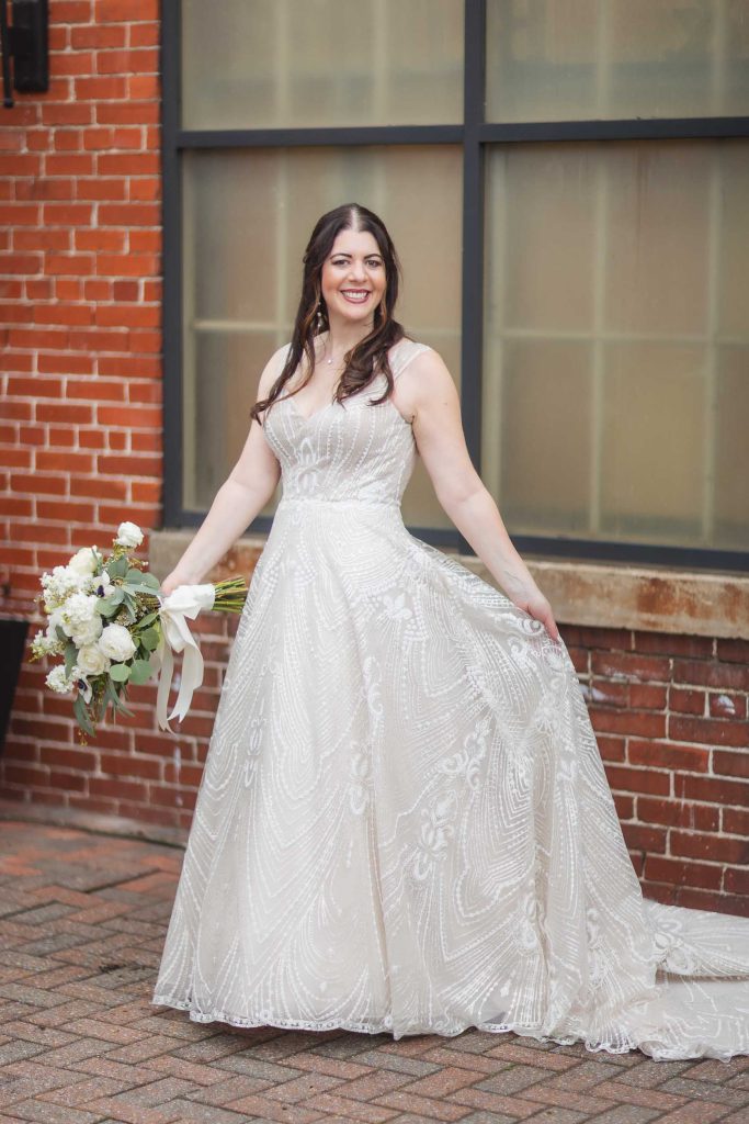 A wedding portrait captures a bride in her beautiful dress posing against the backdrop of Savage Mill's rustic brick building.