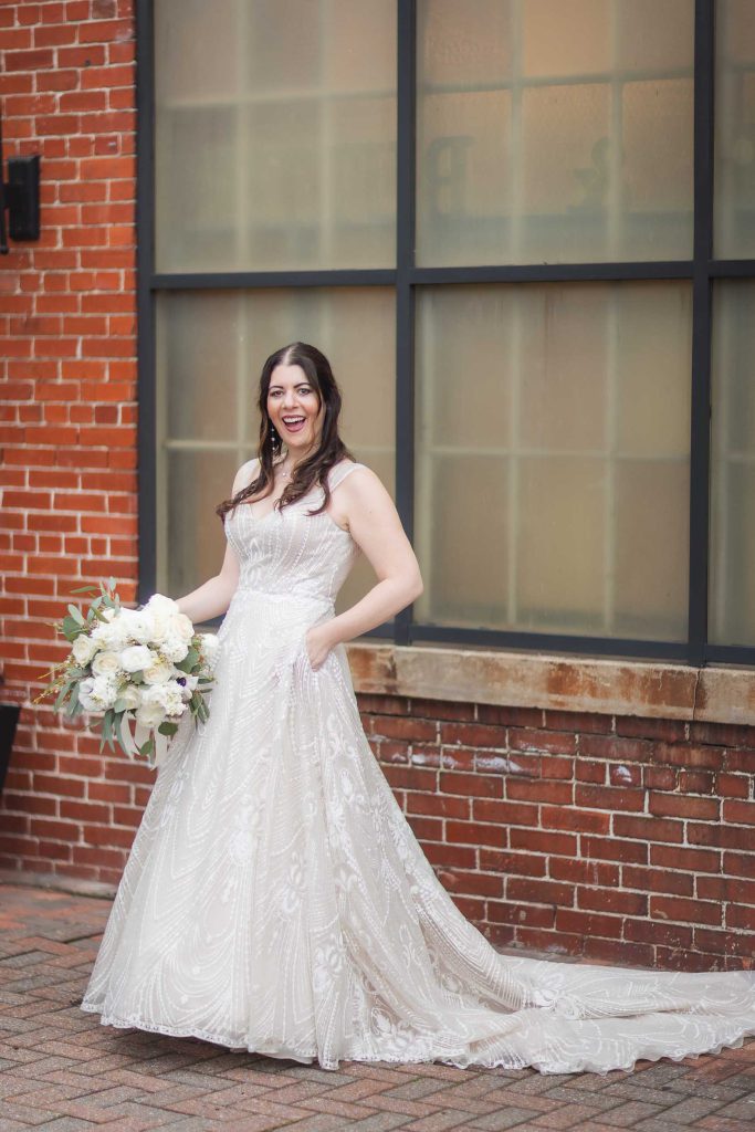 A wedding portrait of a bride smiling in front of Savage Mill.