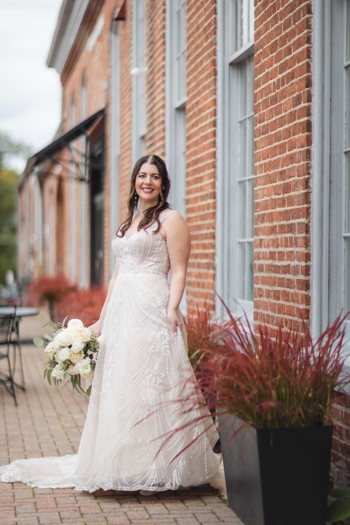 A bride has her portrait taken in front of the historic Savage Mill building.
