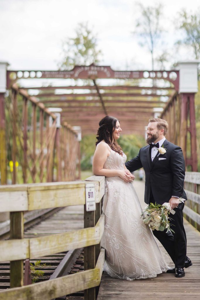 A wedding portrait of a bride and groom standing on a bridge at Savage Mill.