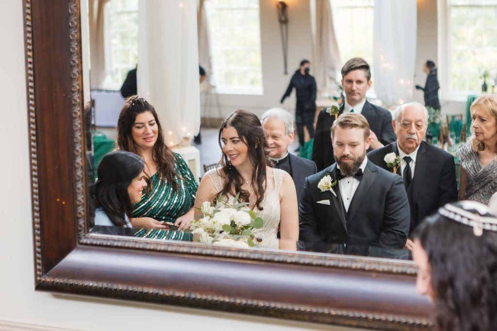 A wedding reception at The Great Room at Savage Mill, with the bride and groom standing in front of a mirror.