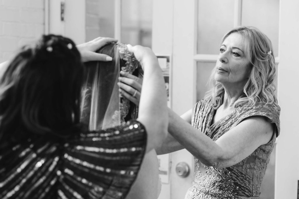 A candid woman getting her hair done in front of a mirror at Savage Mill for a wedding.