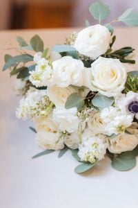 A beautiful bouquet of white flowers and greenery is elegantly displayed on a table, perfectly capturing the intricate details of a wedding at Savage Mill.