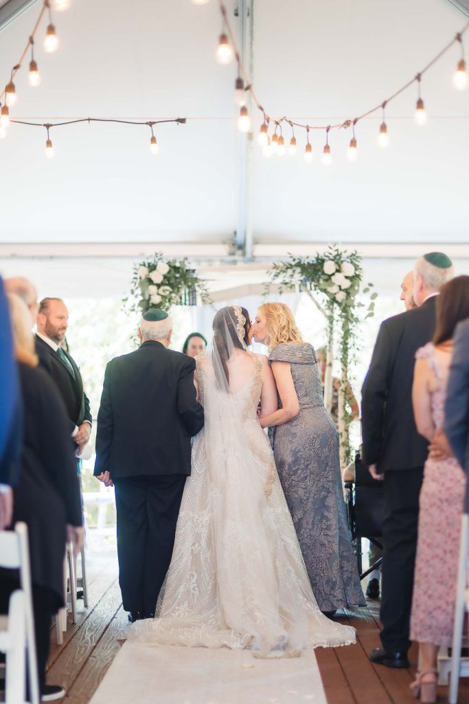 A wedding ceremony at Savage Mill where the bride and groom gracefully walk down the aisle in a beautifully decorated tent.