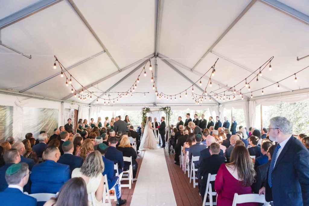 A wedding ceremony at Savage Mill, adorned with string lights.