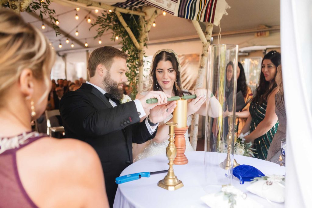 A wedding ceremony at Savage Mill, with the bride and groom lighting a candle in a tent.