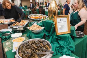 Guests at a wedding reception in Savage Mill gathered around a buffet table, enjoying the delicious spread and engaging in lively conversation.