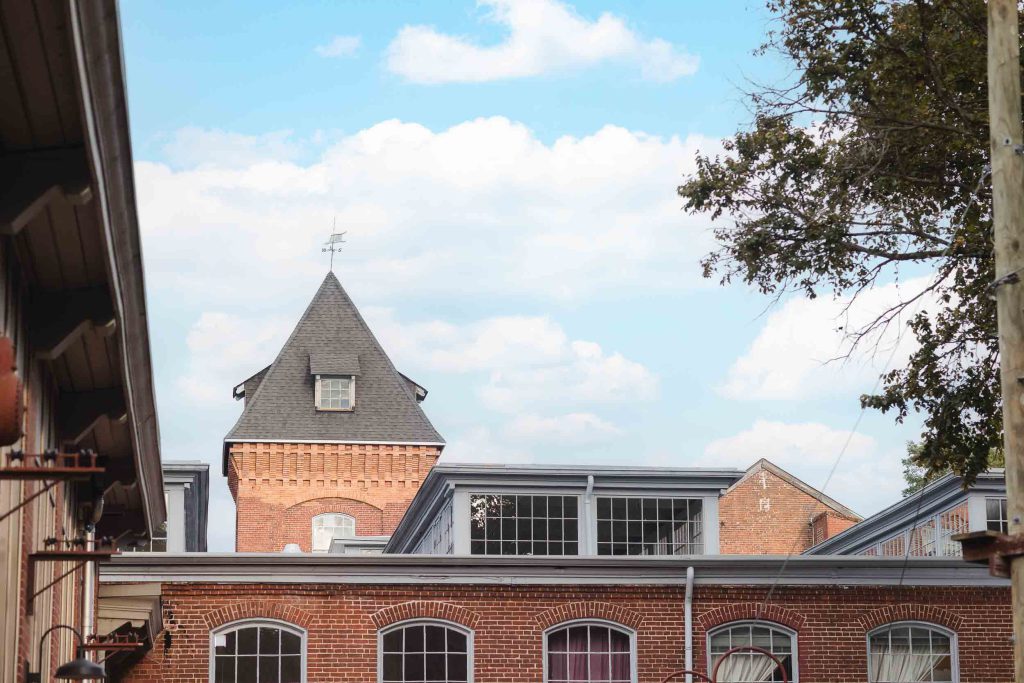 A brick building with a clock tower in the background at Savage Mill, providing a picturesque backdrop for wedding photos and capturing minute details.