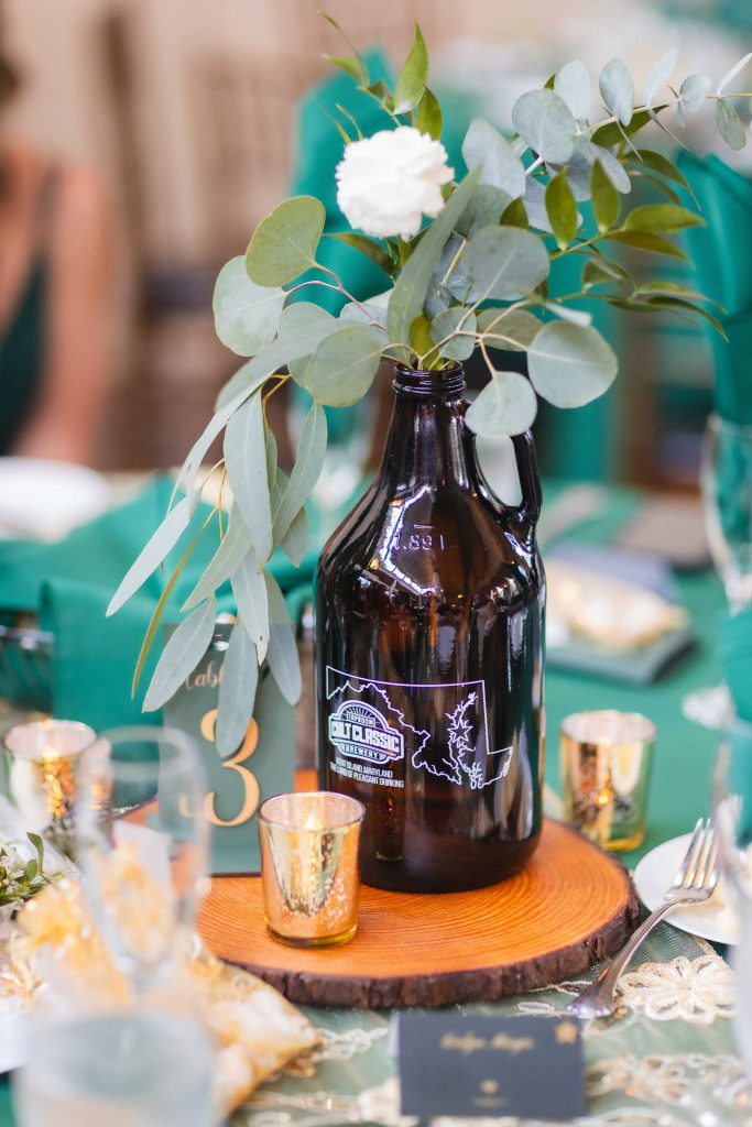 A wedding table setting at Savage Mill, featuring exquisite details. The green table is adorned with a glass jug and eucalyptus, creating a stunning centerpiece.