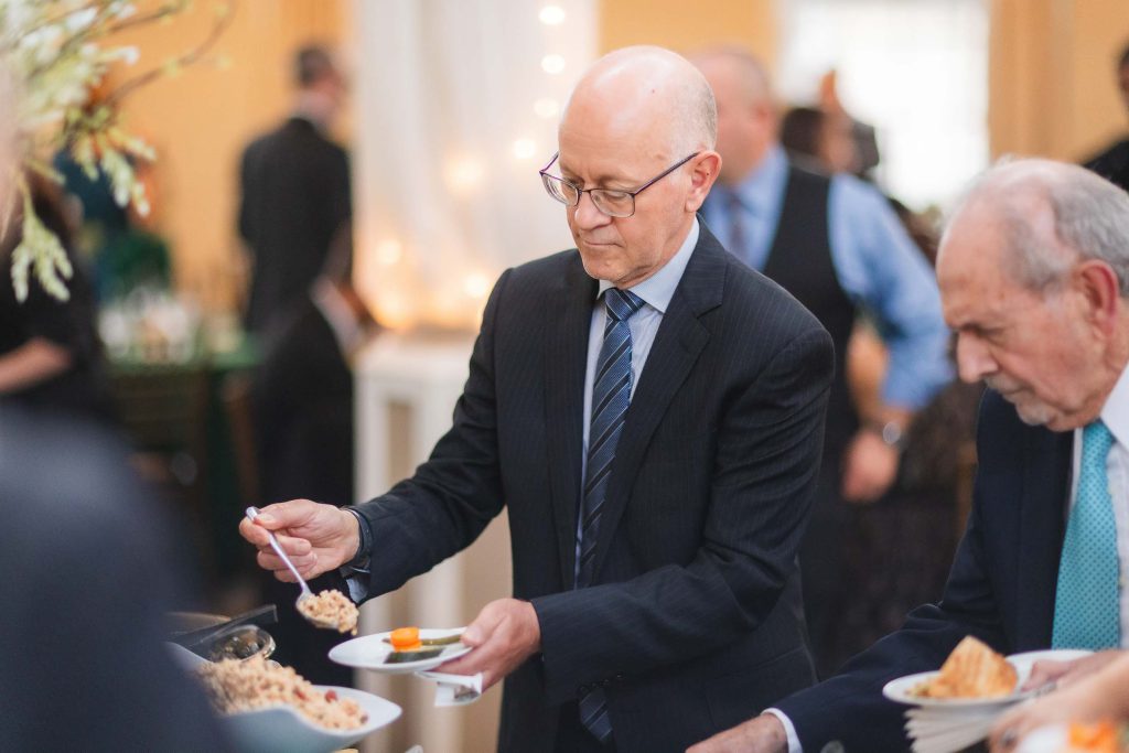 A man serving food to a group of people at a wedding reception.
