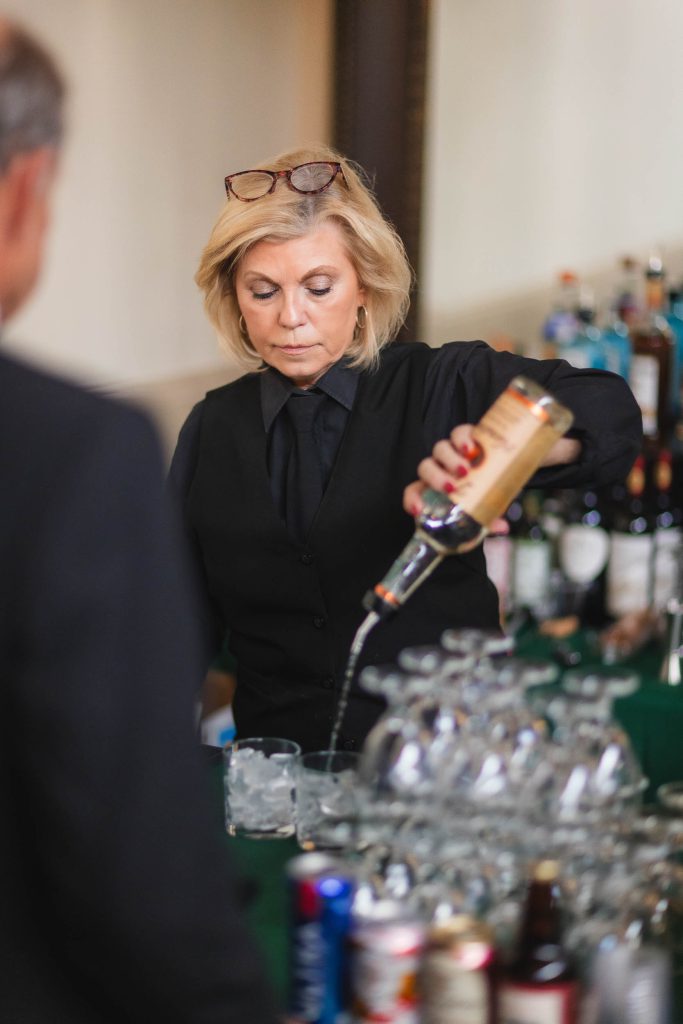 A bartender pouring a drink at a wedding reception.
