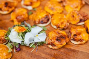 Cheesy appetizers on a wooden cutting board at a wedding.