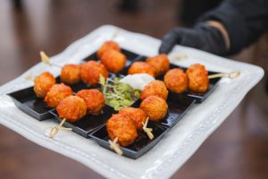 A person is holding a tray of meatballs on skewers at a wedding reception in Savage Mill.