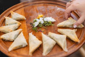 A plate of samosas served at a wedding, displayed on a wooden plate to add intricate details.