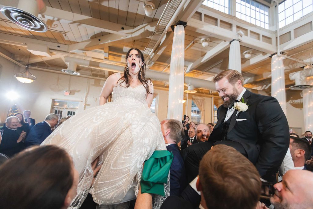 At the Savage Mill wedding reception, a man elegantly carries a bride in her stunning wedding dress.