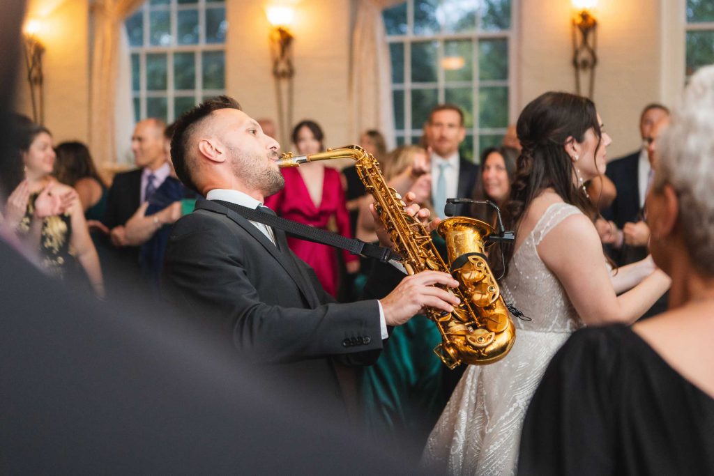 A couple performing a lively saxophone duet at their Savage Mill wedding reception.