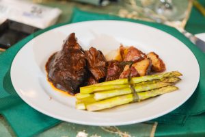 A plate with steak, asparagus and potatoes on it at a wedding celebration.