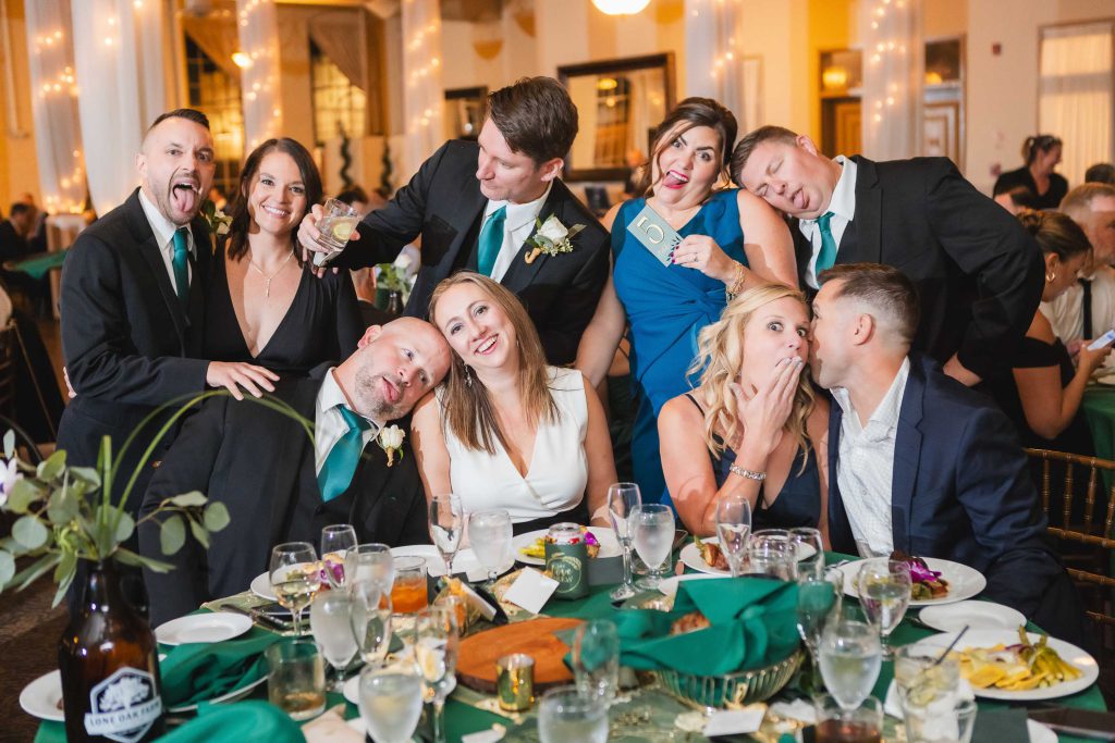 A group of people posing for a photo at a wedding reception in the Great Room at Savage Mill.