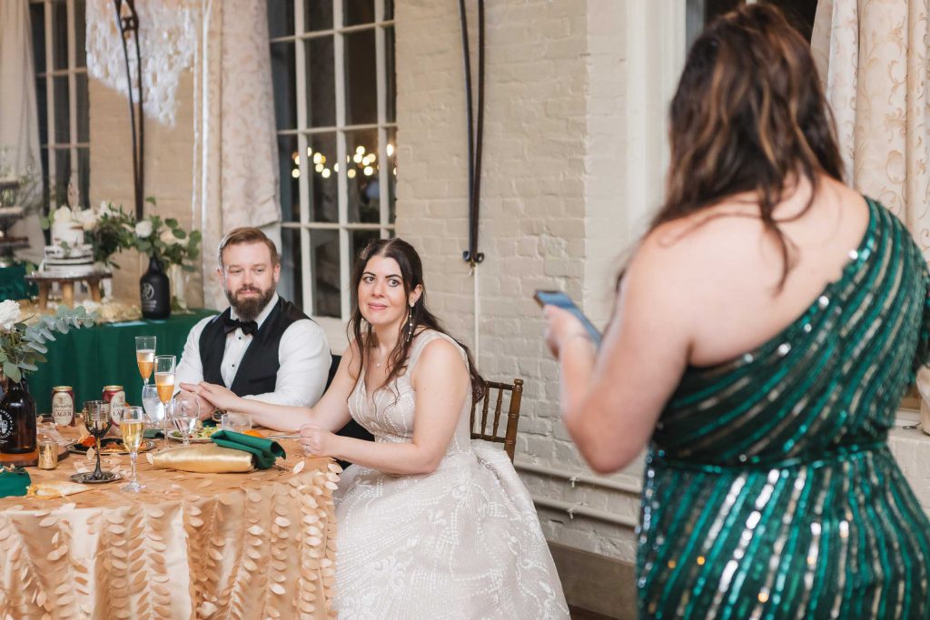 A bride and groom sitting at a table at a wedding reception in Savage Mill.