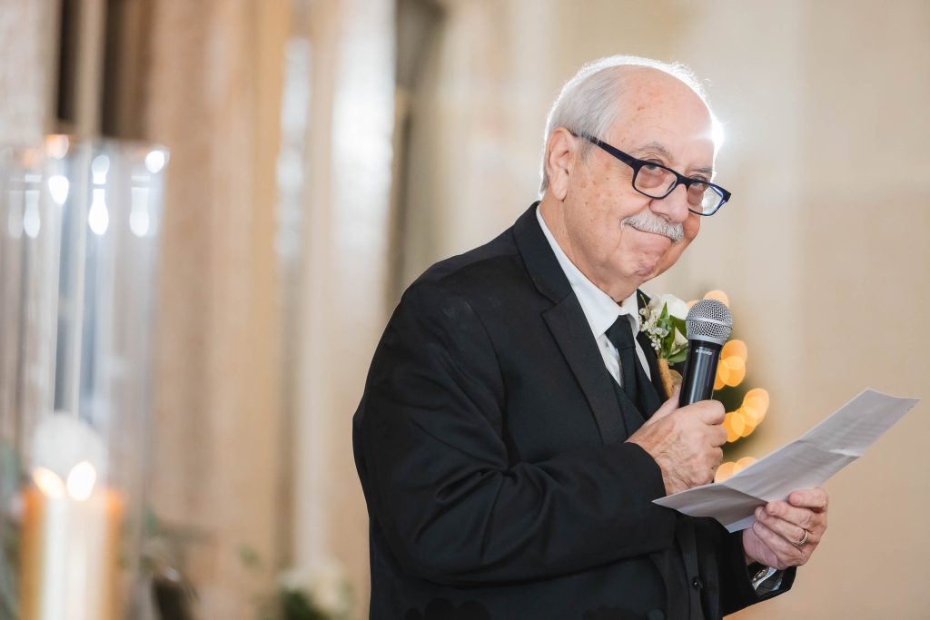 An older man giving a speech at a wedding reception.