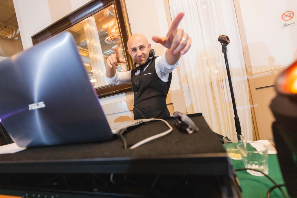 A wedding DJ with a laptop in front of him at Savage Mill.