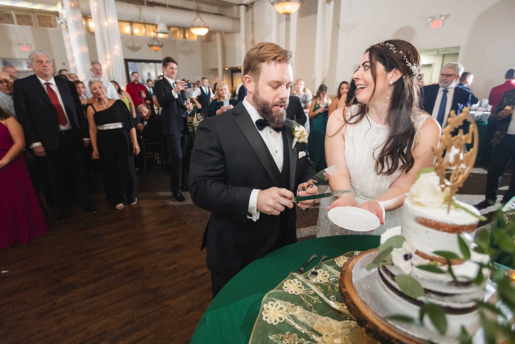 A bride and groom elegantly cutting their wedding cake at the Savage Mill reception.