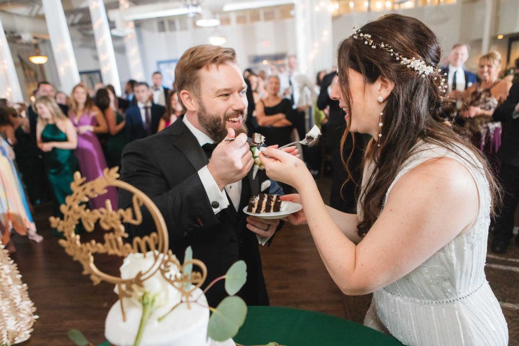 A bride and groom sharing a sweet moment while feeding each other cake at their wedding reception at Savage Mill.