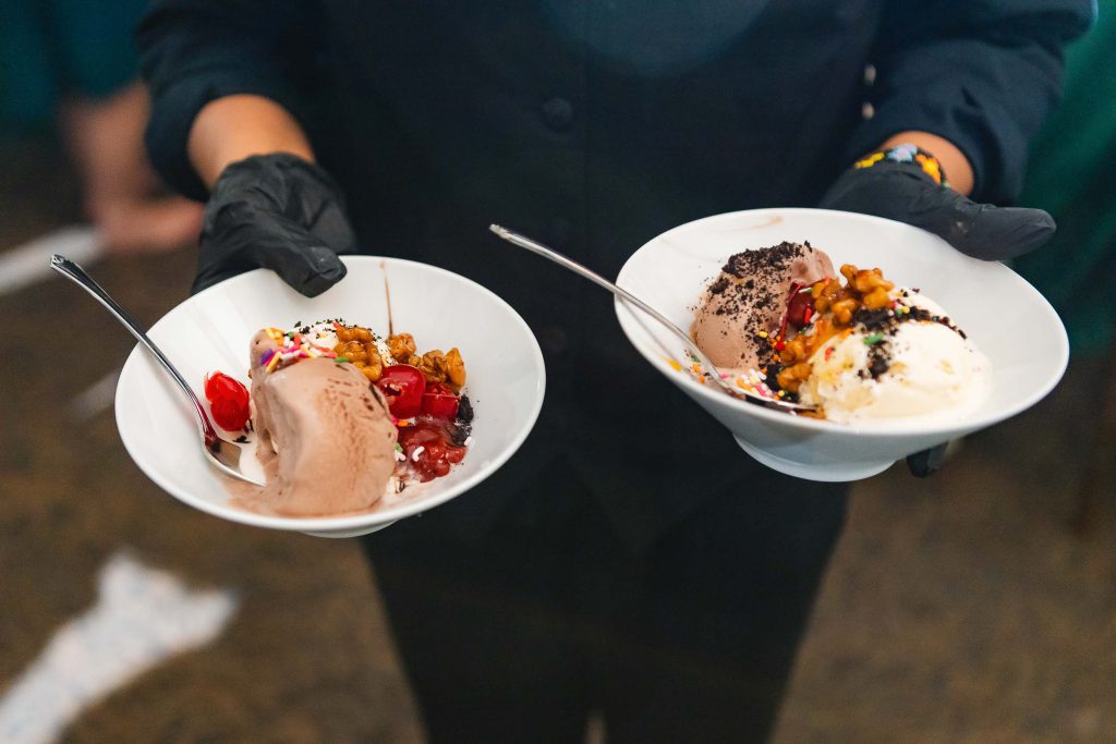 Two waiters at a wedding, holding two bowls of ice cream with exquisite details.