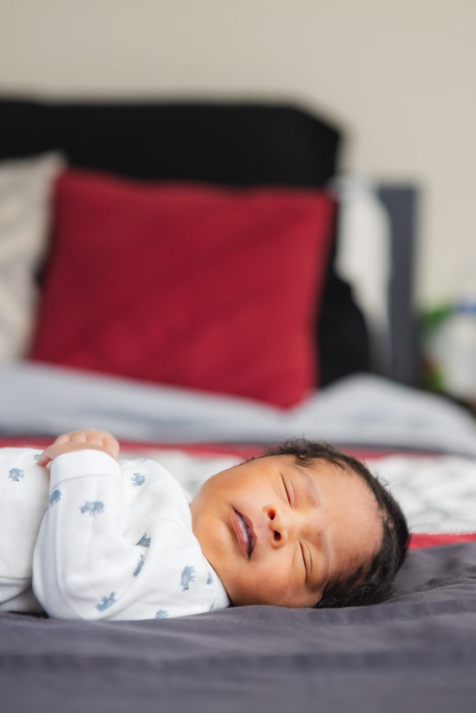 A newborn peacefully sleeping on a bed in a family home's bedroom.