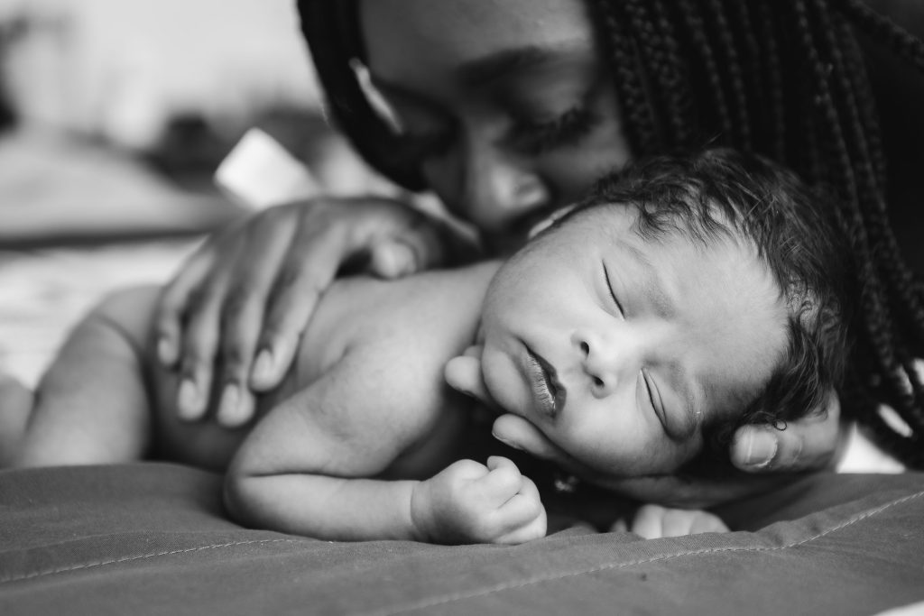 A black and white photo of a woman holding a newborn baby.
