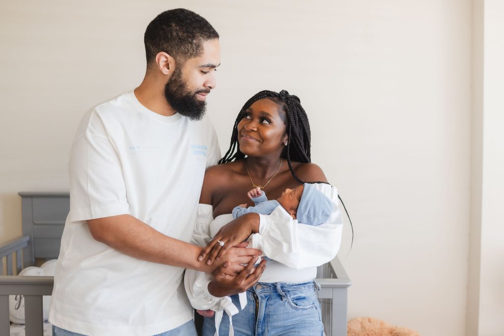 A couple holding a newborn baby in their family home.