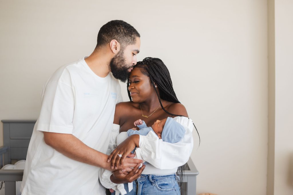 A family is joyfully cradling their newborn baby in the comfort of their home.
