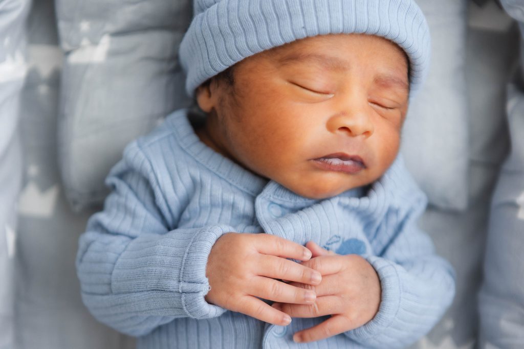 A newborn baby peacefully sleeping in a blue crib in their family home.