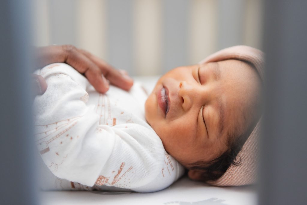 A newborn sleeping peacefully in a crib.
